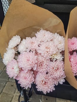 Beautiful gift bouquets of chrysanthemums in brown kraft paper, on the counter of a flower shop, vertical.