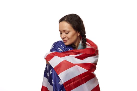 Isolated portrait on white background of a beautiful ethnic middle-aged woman, wrapped in US flag, proud to be american citizen, celebrating the independence day on July 4th. Copy advertising space