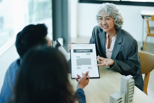 Guarantee Insurance Sign a contract, couple a smiling couple is signing a contract to invest in real estate with the Mortgage officer with the bank.