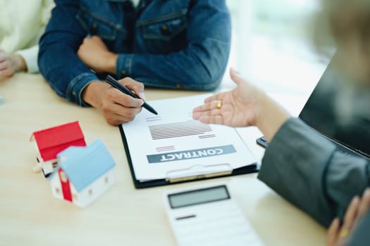 Guarantee Insurance Sign a contract, couple a smiling couple is signing a contract to invest in real estate with the Mortgage officer with the bank.