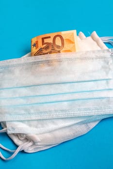 Medical masks and money on a blue background, values in an epidemic