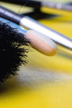 Makeup brushes on a yellow background close up