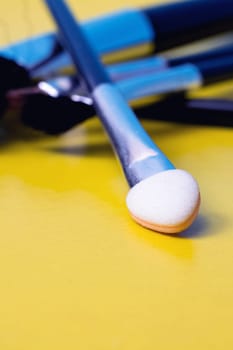 Makeup brushes on a yellow background close up