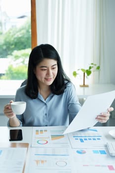 A portrait of an Asian businesswoman showing a happy smiling face holding a cup of coffee during a break.