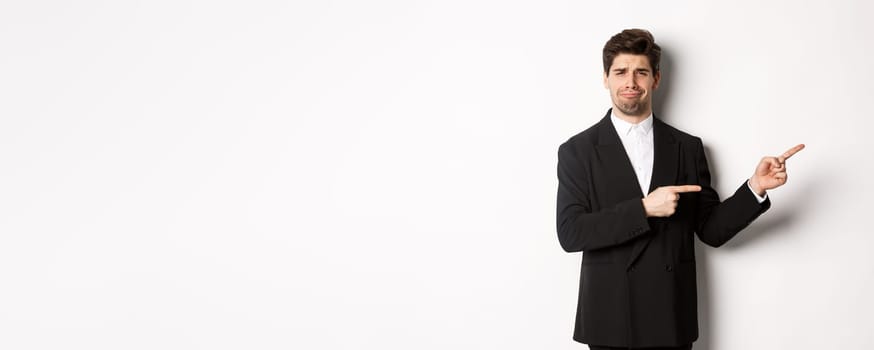 Image of devestated man in party suit, crying and complaining, pointing fingers right at something disappointing, standing over white background.