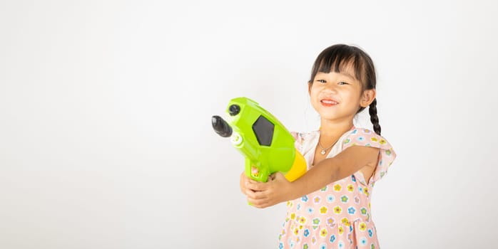 Happy Songkran Day, Asian little girl holding plastic water gun, Thai child funny hold toy water pistol and smile, isolated on white background, Thailand Songkran festival national culture concept