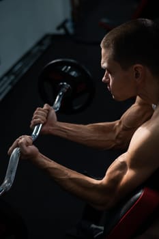 Man doing EZ barbell bicep exercises on Scott bench