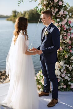 wedding ceremony on a high pier near the river with invited guests