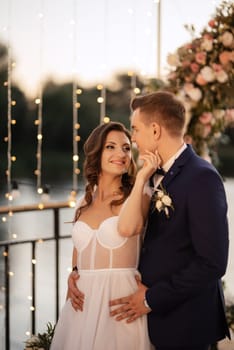 bride and groom against the backdrop of a yellow sunset on a pier near the river