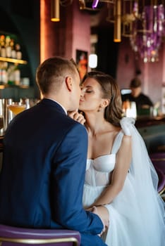 bride and groom inside a cocktail bar in a bright atmosphere with a glass of drink