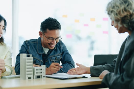 Guarantee Insurance Sign a contract, couple a smiling couple is signing a contract to invest in real estate with the Mortgage officer with the bank.