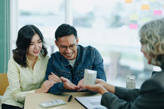 Guarantee Insurance Sign a contract, couple a smiling couple is signing a contract to invest in real estate with the Mortgage officer with the bank.