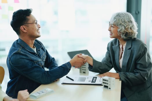 The bank's Mortgage Officers shake hands with customers to congratulate them after signing a housing investment loan agreement.