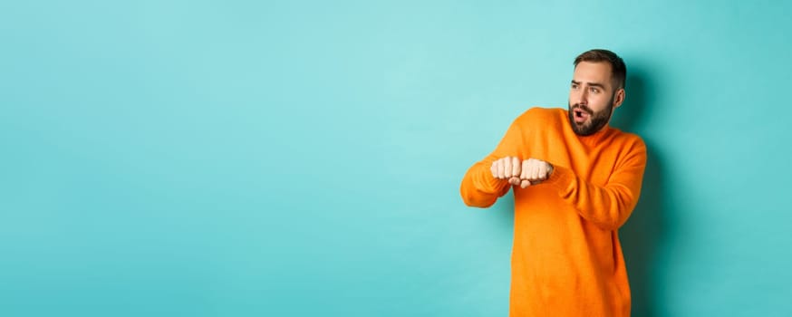 Happy young man do champion dance, celebrating victory or success, light blue background.