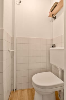 a small bathroom with white tile walls and wood flooring on the wall, along with a toilet in the corner