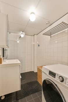 a laundry room with a washer and dryer on the floor in front of the sink is black tile