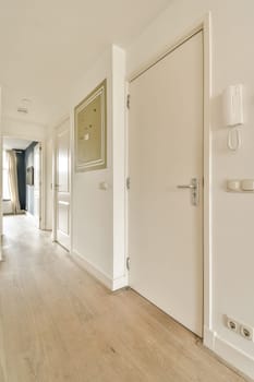 an empty room with white walls and wood flooring the door is open to reveal a hallway that leads to another room