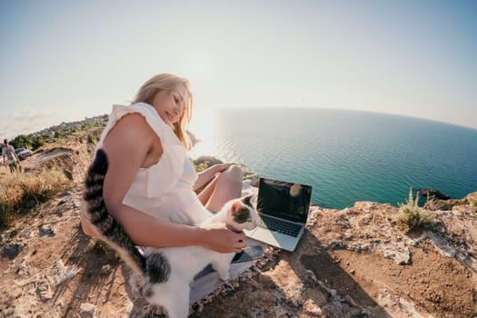 Woman sea laptop. Business woman in yellow hat working on laptop by sea. Close up on hands of pretty lady typing on computer outdoors summer day. Freelance, digital nomad, travel and holidays concept.