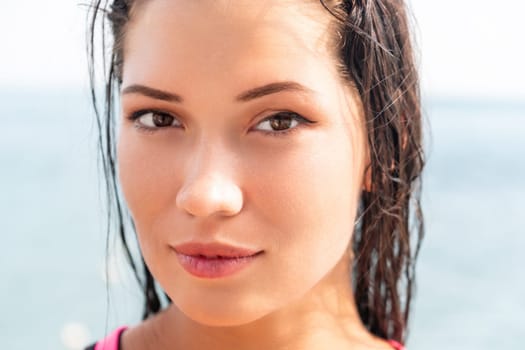 Woman sea sup. Close up portrait of beautiful young caucasian woman with black hair and freckles looking at camera and smiling. Cute woman portrait in a pink bikini posing on sup board in the sea