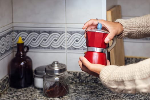 hands of an unrecognizable man closing the italian pot to make the coffee in the kitchen, concept of real people lifestyle at home