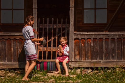 mother and daughter in Ukrainian folk dresses on the threshold of the house.