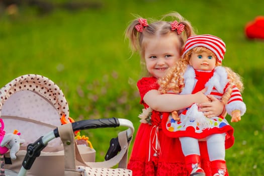 The girl plays with a doll in nature, holding her in her arms