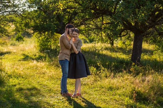 man tells in his ear the secret of his girlfriend walking in the park