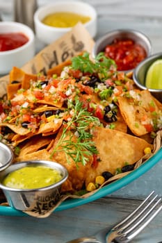 Traditional mexican food nachos with various sauces on wooden table