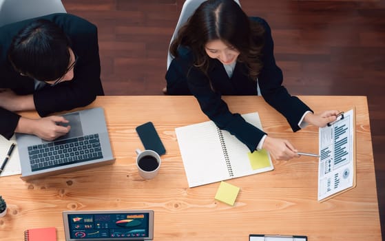 Top-view business team of financial data analysis meeting with business intelligence, report paper and dashboard on laptop for marketing strategy. Business people working together in office of harmony