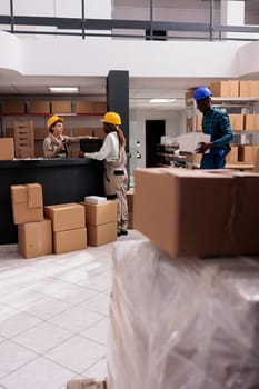 Shipping department operators packing order in cardboard box and checking barcode at registration desk. Diverse man and women delivery managers team working in distribution center warehouse