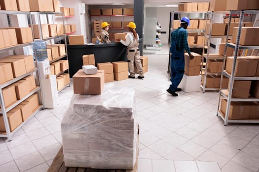 Post office storage workers managing parcels delivery, carrying and packing cardboard boxes. Logistics department employees preparing freight for distribution in industrial warehouse