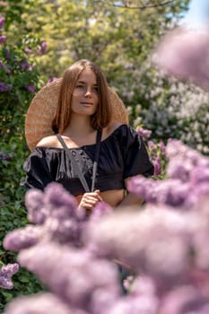 portrait of young woman with long hair outdoors in blooming lilac garden.