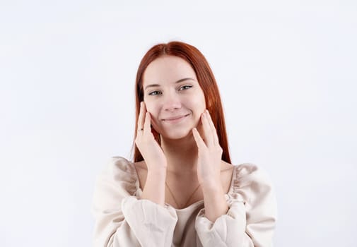 Happy beautiful caucasian woman smiling touching her face over white background, copy space