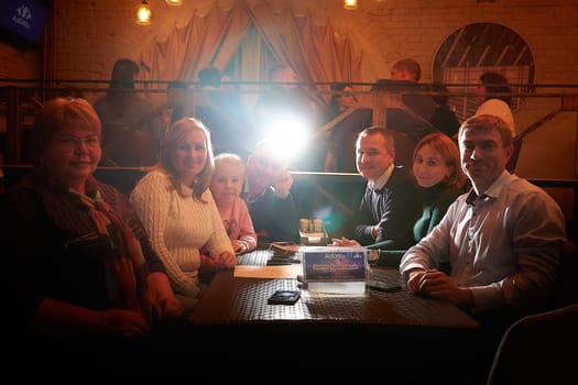 Kirov, Russia - September 13, 2022: People at table in small cafe or restaurant during intellectual game. Hungry group discussing the menu in the restaurant and waiting for waiter to get food