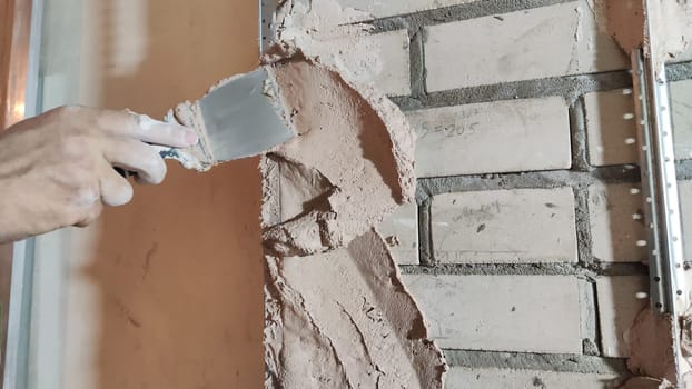 Close-up hand of man applying putty with a spatula. Home repair, decorative plaster on wall. Partial focus and blur for showing movement