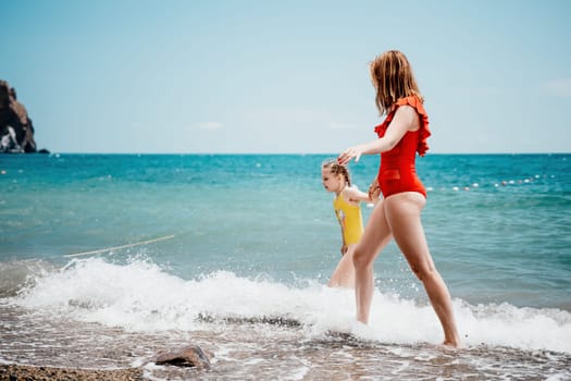 Happy loving family mother and daughter having fun together on the beach. Mum playing with her kid in holiday vacation next to the ocean - Family lifestyle and love concept.