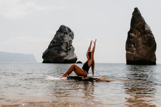 Woman travel sea. Young Happy woman in a long red dress posing on a beach near the sea on background of volcanic rocks, like in Iceland, sharing travel adventure journey