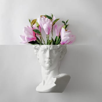 David's statue bust of Michelangelo and a bouquet of flowers like a brain. Minimal playful concept of spring gift and creativity and art. High quality photo