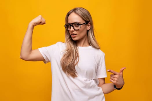 girl student in glasses and a white T-shirt on a studio yellow background.