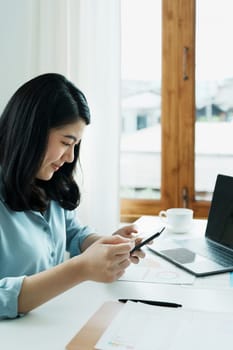 Portrait of young Asian woman using credit card and phone for online shopping.