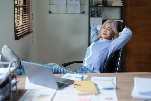 Portrait of a woman business owner showing a happy smiling face as he has successfully invested her business using computers and financial budget documents at work.