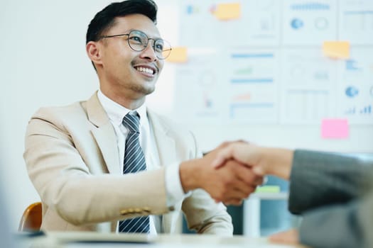 Asian entrepreneurs handshakes to congratulate the agreement between the two companies to enhance investment and financial strength. deal concept.