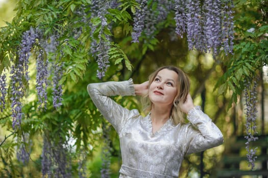 Wisteria woman. Thoughtful happy mature woman surrounded by chinese wisteria.