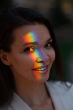 Portrait of caucasian woman with rainbow beam on her face outdoors