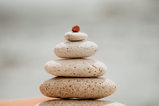 Pyramid stones on the seashore with warm sunset on the sea background. Happy holidays. Pebble beach, calm sea, travel destination. Concept of happy vacation on the sea, meditation, spa, calmness.