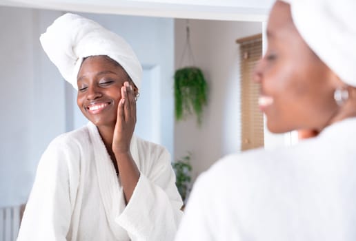 Skincare, face and cosmetic cream of an African woman using facial beauty products for morning self care. Female with a smile health and wellness in a home bathroom.