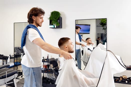 Professional barber during work with man client in barber shop.