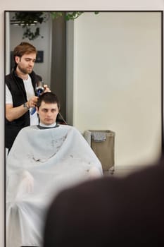 Professional hairdresser during work with man client with hair dryer in barber shop. Haircut in the barbershop.