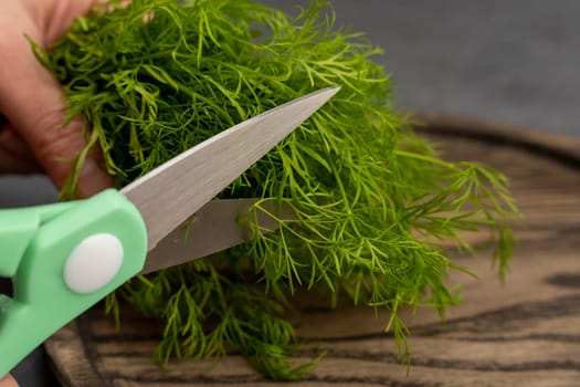 kitchen scissors cutting dill in the kitchen on a cutting board in the kitchen. Close-up of kitchen accessories. cooking. Fresh greens. Healthy eating. top side view