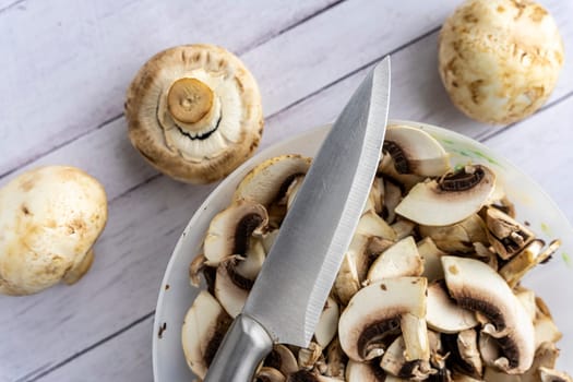 a bowl with pieces of fresh mushrooms. cut the mushrooms with a knife. Cooking mushroom dishes. Cooking dinner in the kitchen. Champignons